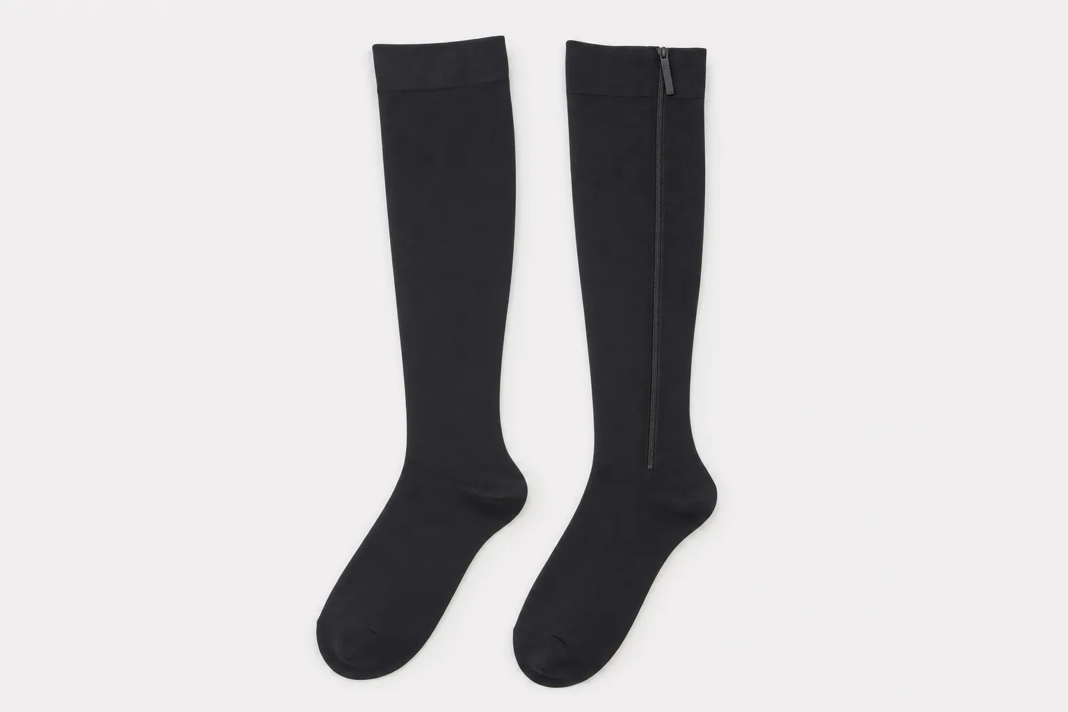 A zipper compression sock and a regular pull-on compression sock laid side by side on a table