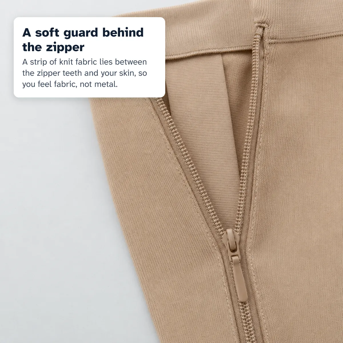 Close-up of a part-open zipper showing the soft knit guard between the teeth and the skin